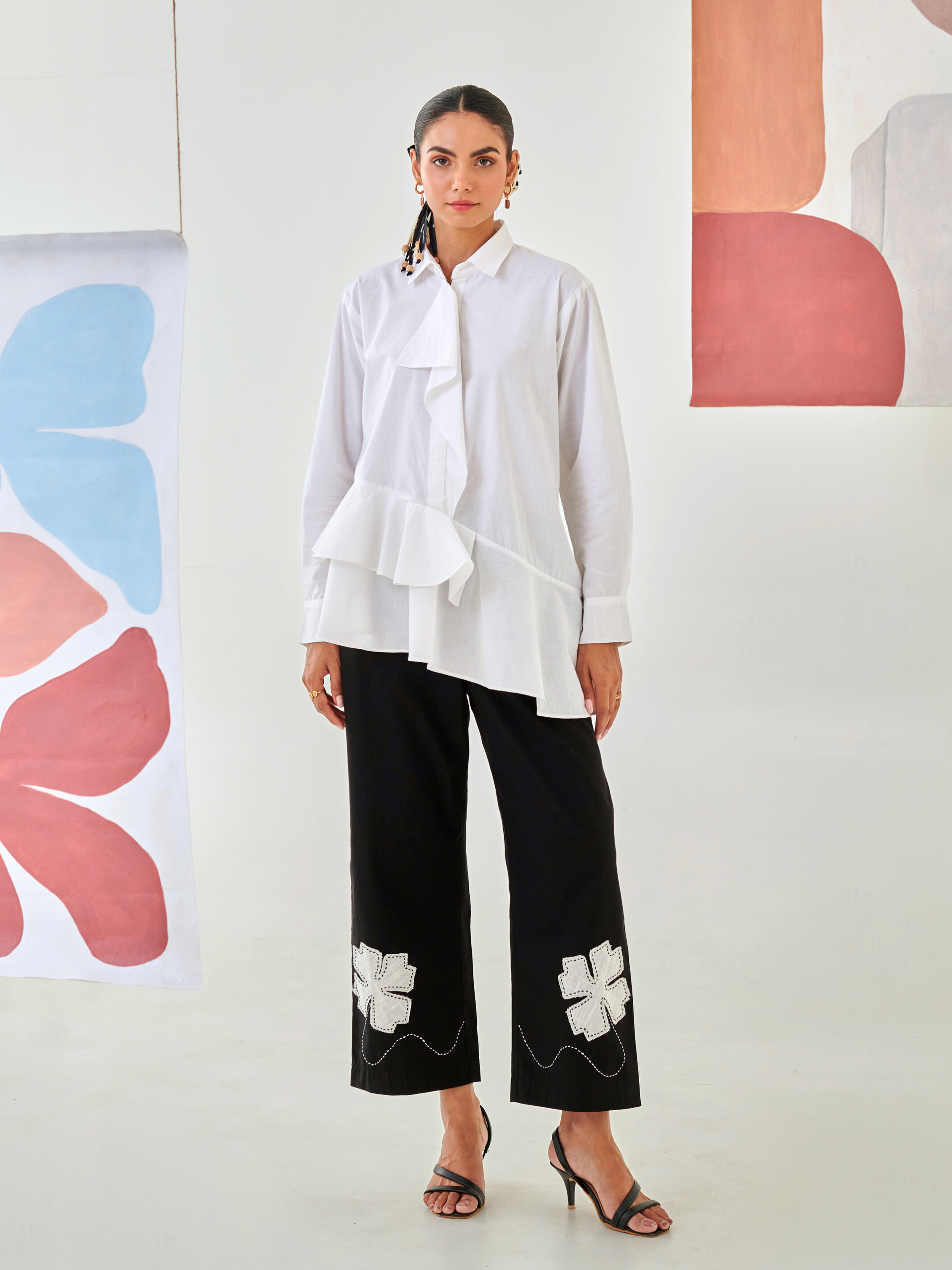 White asymmetric shirt paired with black pants with floral patch detail