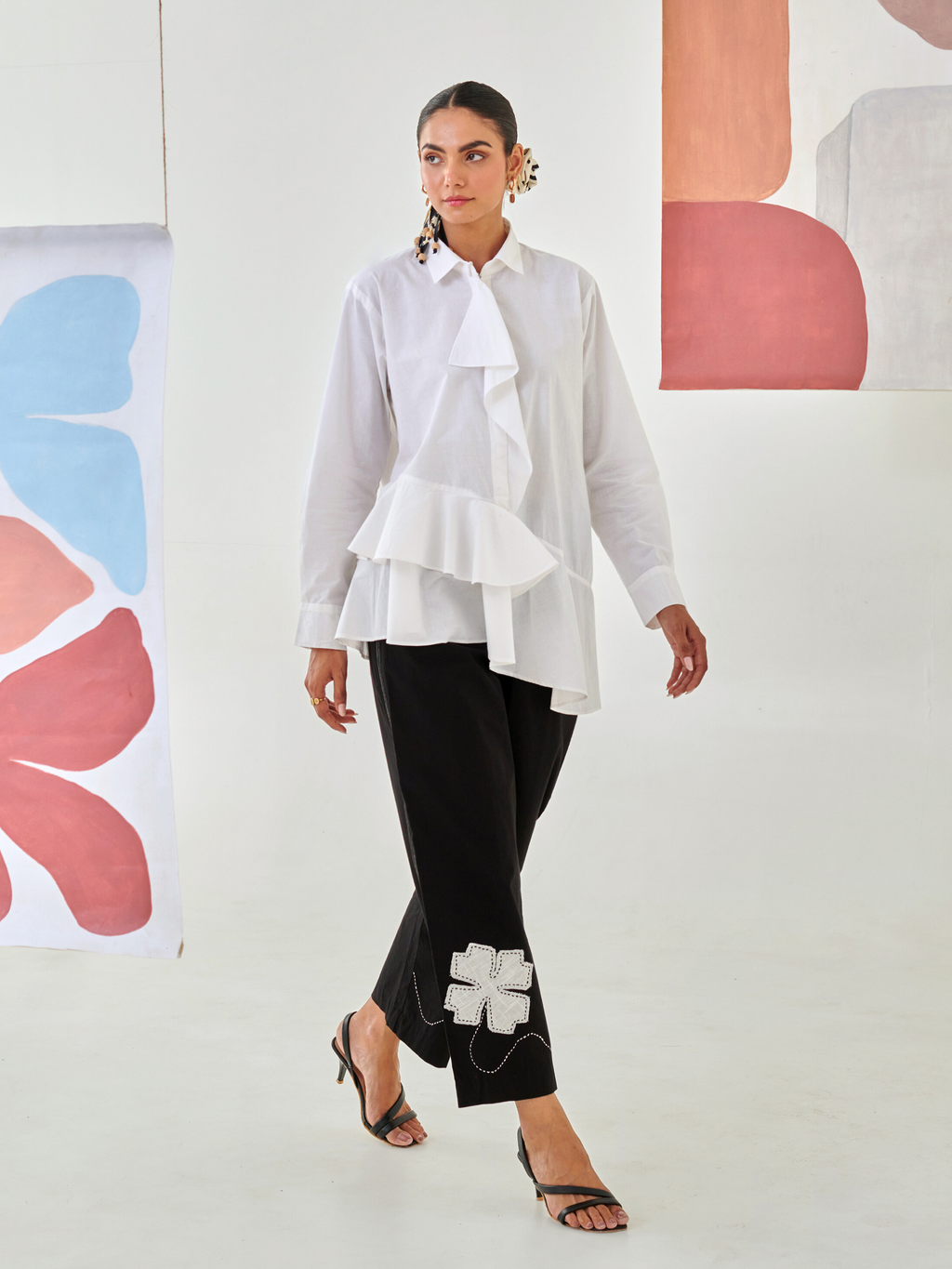 White asymmetric shirt paired with black pants with floral patch detail